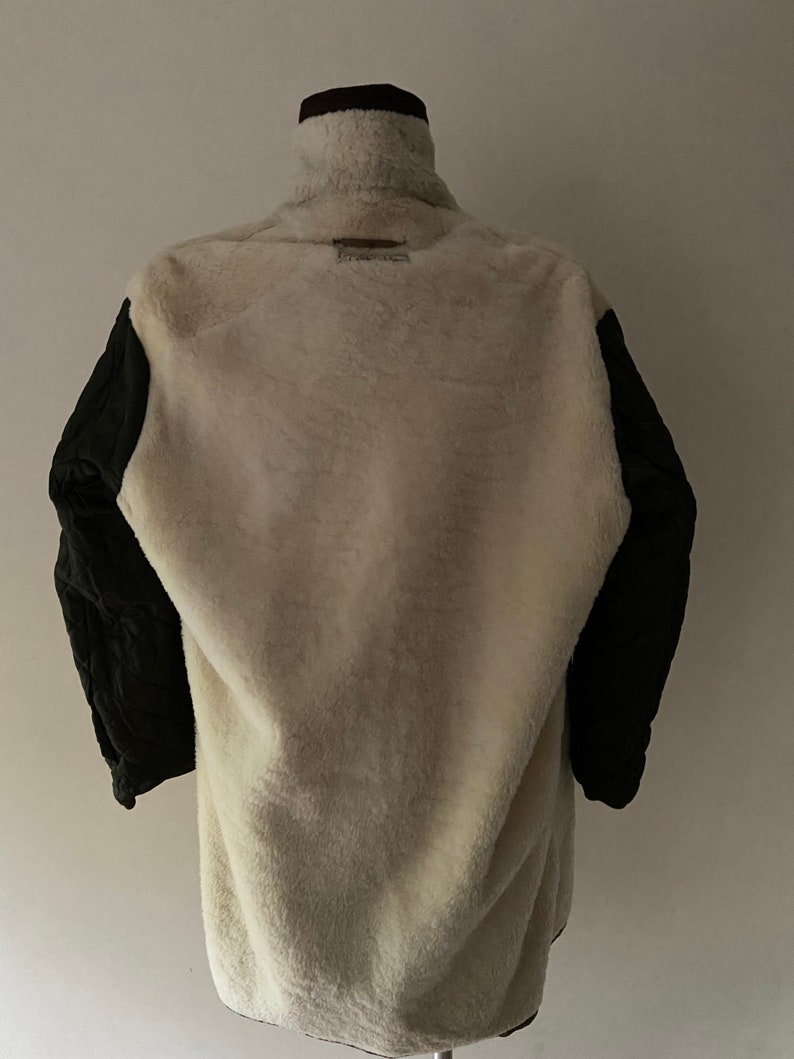 Puede incluir: Una chaqueta marr&oacute;n, blanca y negra con forro polar. La chaqueta tiene un cuello alto y una cremallera.