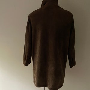 Puede incluir: Una chaqueta de ante marr&oacute;n con cuello alto y mangas largas.