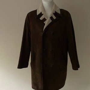 Puede incluir: Una chaqueta de ante marr&oacute;n con cuello de piel sint&eacute;tica blanca. La chaqueta tiene cierre de doble botonadura y dos bolsillos.