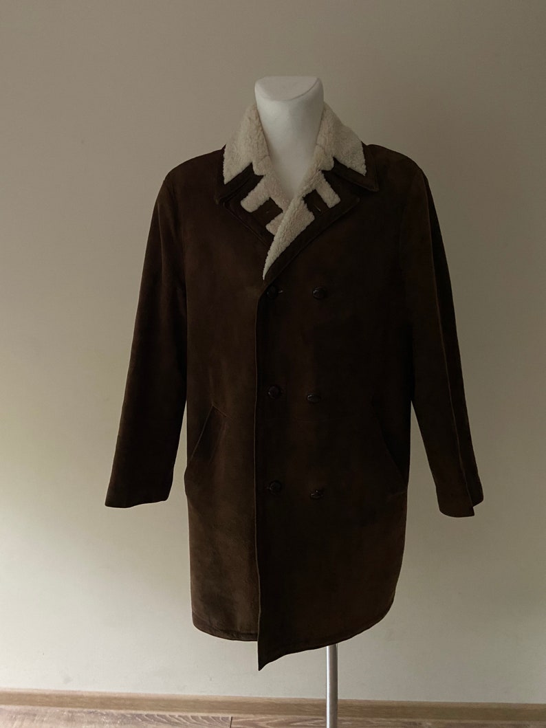 Puede incluir: Una chaqueta de ante marr&oacute;n con cuello de piel sint&eacute;tica blanca. La chaqueta tiene cierre de doble botonadura y dos bolsillos.