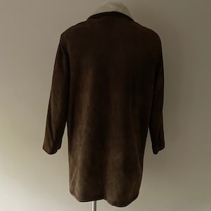 Puede incluir: Una chaqueta de ante marr&oacute;n con cuello de piel blanca.