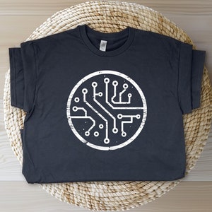 May include: A dark gray t-shirt with a white circular design of a circuit board. The design has a distressed look.