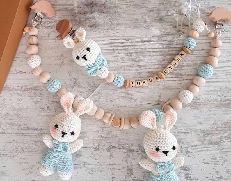 May include: Two crocheted bunny toys with blue and white outfits attached to wooden bead chains with the names "Yusuf" and "Eymen" spelled out in wooden letters.