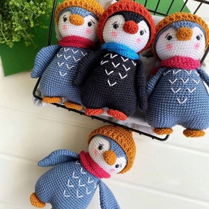 May include: Four crocheted penguin toys with different colored hats and scarves. The penguins are sitting in a black wire basket.