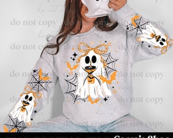 May include: A light gray crewneck sweatshirt featuring a graphic print of white ghosts with black eyes, orange patterned bows, black spiderwebs, and orange bats. The design is repeated on the chest and both sleeves, incorporating small black and orange stars.