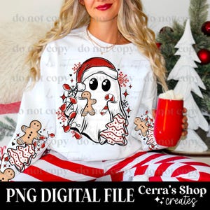 May include: White Christmas-themed sweatshirt featuring a ghost wearing a Santa hat, holding a gingerbread man, candy cane, and Christmas tree. The sleeves display gingerbread men and Christmas trees. The text "PNG DIGITAL FILE" and "Cerra's Shop creates" are visible.