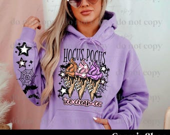 May include: A light purple hoodie with a graphic featuring the text "Hocus Pocus" above three ice cream cones with skeleton hands. The sleeves have star and spiderweb designs. The text "ice cream co." is below the cones.