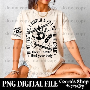 May include: Cream-colored t-shirt with a graphic design featuring a handprint, knife, and text that reads "I watch a lot of true crime, don't test me, they'll never find your body." The design includes crime scene elements.