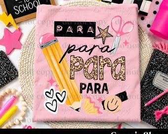 May include: A light pink t-shirt featuring a graphic design with a yellow pencil, pink scissors, a leopard print pattern, and a smiley face. The text reads "PARA" in various fonts and styles, including black block letters and leopard print fill.