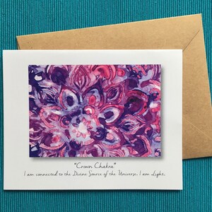 May include: A white card with a purple and pink mandala design. The text "Crown Chakra" and "I am connected to the Divine Source of the Universe, I am Light." is printed on the card.