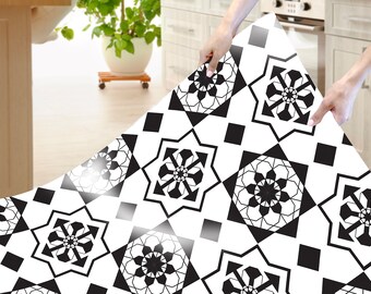 May include: Black and white patterned floor tile sticker. The sticker is being applied to a white floor. The sticker has a geometric design with black and white squares and stars.