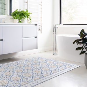 Peut inclure: Une salle de bain blanche avec une baignoire blanche, un meuble-lavabo blanc avec un double lavabo et un tapis à motifs au sol. Il y a des plantes dans la salle de bain.