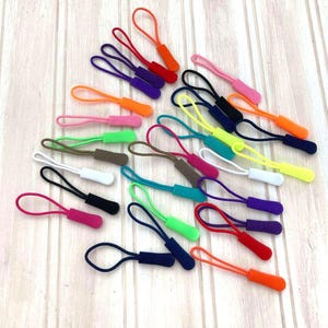 May include: Assortment of colourful zipper pulls in various colours, including pink, green, blue, yellow, orange, and purple. The zipper pulls are made of a soft, flexible material and are perfect for adding a pop of colour to any project.