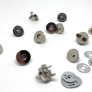 May include: A set of silver magnetic snaps for sewing projects. The set includes both male and female snaps, as well as a pack of metal washers.