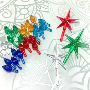 May include: Assortment of colourful Christmas tree topper bulbs and star-shaped ornaments. The bulbs are in various colours, including clear, red, blue, green, and yellow. The stars are red, green, and clear.