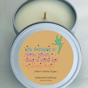 May include: A light blue candle tin with a lid featuring the quote "All it takes is faith, trust, and a little bit of pixie dust." The candle is scented "Warm Vanilla Sugar" and has a green fairy graphic.