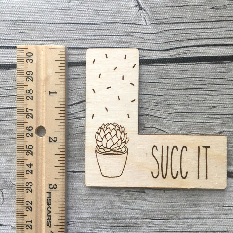 K&ouml;nnte beinhalten: Ein Holzschild mit einer Illustration einer Sukkulente und dem Text "SUCC IT".