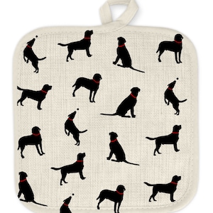 May include: A white cotton pot holder with a black silhouette pattern of Labrador Retrievers wearing red collars. The dogs are in various poses, including sitting, standing, and playing fetch.