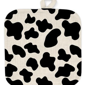 May include: A white and black cow print pot holder with a loop handle.