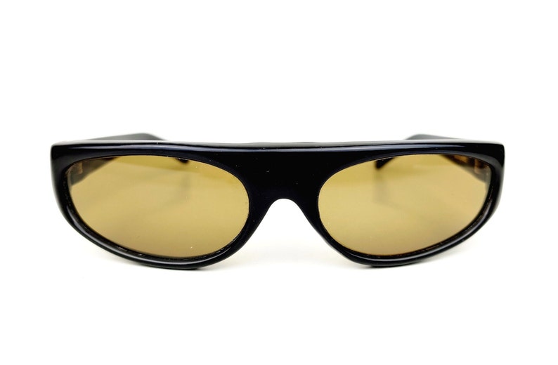 May include: Black sunglasses with brown lenses and a curved, oval shape.