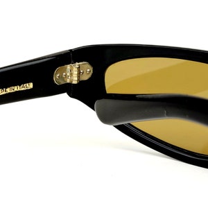 May include: Black sunglasses with a gold hinge and the text "MADE IN ITALY" on the arm.