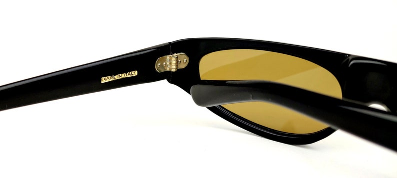 May include: Black sunglasses with a gold hinge and the text "MADE IN ITALY" on the arm.