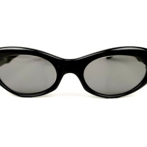 May include: Black oval-shaped sunglasses with a thin black frame and dark gray lenses.