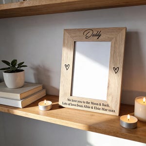 May include: A light oak picture frame with the word "Daddy" in script. The frame has two heart symbols and the text "We love you to the Moon & Back, Lots of love from Albie & Elsie-Mae xxxx".
