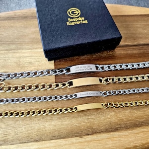 Peut inclure: Quatre bracelets chaîne personnalisés, argentés et dorés, avec plaques gravées. L'un des bracelets porte l'inscription "Jack on your 18th Love Mum & Dad". Un coffret noir avec lettrage doré est en arrière-plan.