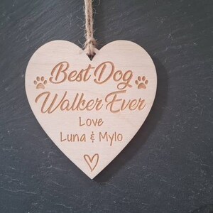Puede incluir: Un letrero de madera en forma de coraz&oacute;n con el texto "Best Dog Walker Ever" y "Love Luna & Mylo" con huellas de patas y un peque&ntilde;o coraz&oacute;n.