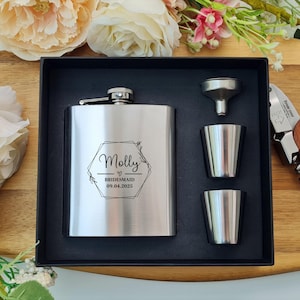 May include: A stainless steel hip flask gift set with a personalised inscription that reads "Molly Bridesmaid 09.04.2023". The set includes a funnel, two shot glasses, and a corkscrew.