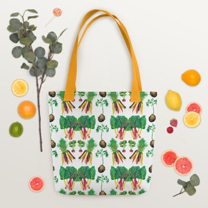 May include: A white tote bag with a colorful vegetable pattern. The bag has a yellow handle and features a repeating pattern of carrots, radishes, and leafy greens.