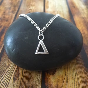 May include: A silver chain necklace with a triangle pendant. The pendant is hollow and has a geometric design.