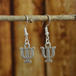 May include: A pair of silver earrings with a Greek letter psi charm hanging from each earring.