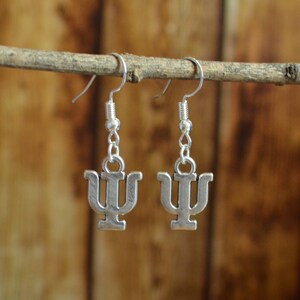 May include: A pair of silver earrings with a Greek letter psi charm hanging from a silver hook.
