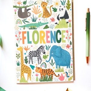 K&ouml;nnte beinhalten: Eine bunte Karte mit dem Namen "FLORENCE" in Regenbogenfarben. Die Karte zeigt eine Dschungelszene mit Tieren wie einer Giraffe, einem Zebra, einem Elefanten, einem Tiger, einem Faultier, einem Panda und einem Krokodil. Der Hintergrund ist wei&szlig; mit gr&uuml;nen Bl&auml;ttern, Blumen und Sternen.