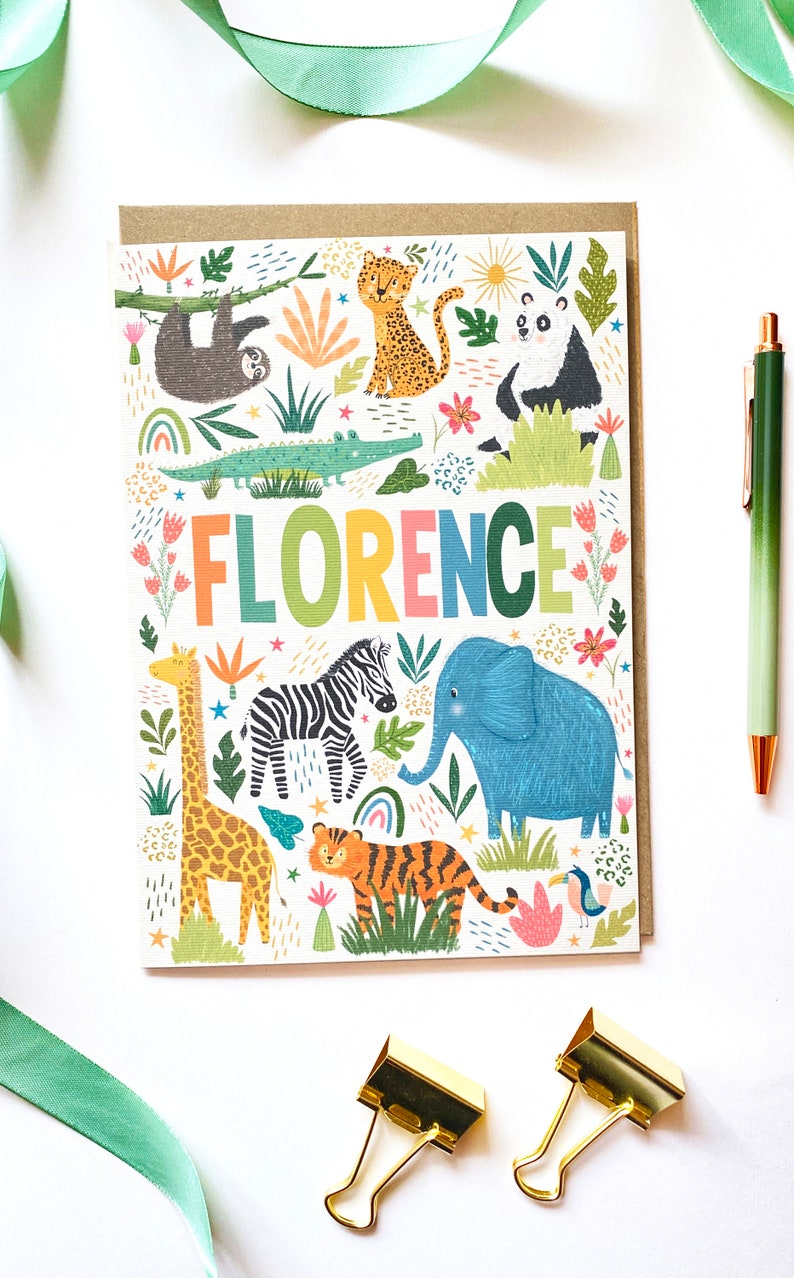 K&ouml;nnte beinhalten: Eine bunte Karte mit dem Namen "FLORENCE" in Regenbogenfarben. Die Karte zeigt eine Dschungelszene mit Tieren wie einer Giraffe, einem Zebra, einem Elefanten, einem Tiger, einem Faultier, einem Panda und einem Krokodil. Der Hintergrund ist wei&szlig; mit gr&uuml;nen Bl&auml;ttern, Blumen und Sternen.