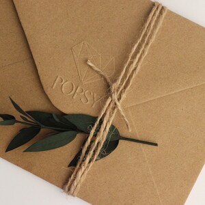 May include: A brown paper envelope with a twine bow and a green sprig of leaves. The envelope has a raised logo that says "POPSY" with a geometric design.