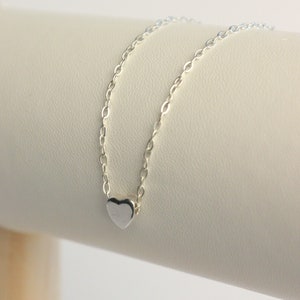 May include: A delicate silver chain necklace with a small, silver heart pendant.