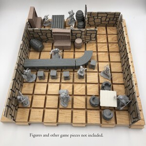 May include: A wooden game board with a grid pattern and stone walls. The board is designed for role-playing games and includes a bar, barrels, and other game pieces.  "Figures and other game pieces not included."