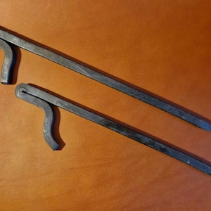 May include: Two black metal tent pegs with a hook on one end. The pegs are approximately 30 cm long.