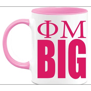 May include: White ceramic mug with a pink interior, handle, and the text "ΦM BIG" in a bold, hot pink font. The mug is designed for hot or cold beverages.