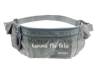 May include: Gray fanny pack with two zippered compartments and an adjustable strap. The text "Gamma Phi Beta" is printed on the front, with "SPORT" below it. The bag is made of a textured material and has a silver-colored zipper.