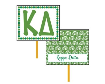 May include: Two green and white signs with the letters "KD" and the words "Kappa Delta" on them. The signs are on wooden sticks.