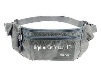 May include: Gray fanny pack with two zippered compartments and an adjustable strap. The text "Alpha Omicron Pi" is printed on the front, with "SPORT" below it. The pack has a diamond pattern.