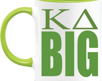 May include: White ceramic mug with a green interior, handle, and rim. The mug features the Greek letters Kappa Delta and the word "BIG" in green block letters. A simple and bold design.