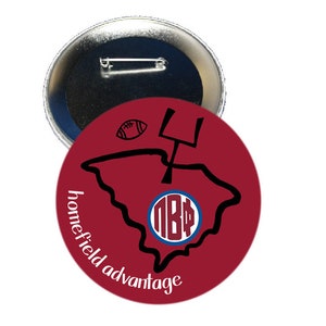 May include: A round button with a pin back. The button has a maroon background with a black outline of a state, a football, and a goalpost. The text "homefield advantage" is in white, and a circular design with the letters "NBP" is in the center.