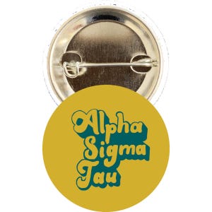 May include: A circular badge with a mustard yellow face and teal text reading "Alpha Sigma Tau". The badge has a metal pin fastening on the reverse.