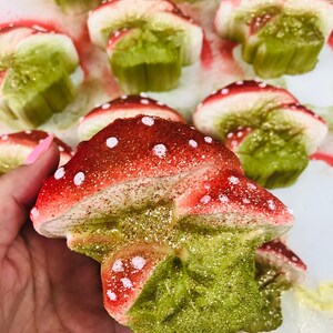 May include: A collection of red and green glitter mushroom shaped ornaments. The mushrooms have white polka dots and are made of a soft, spongy material.