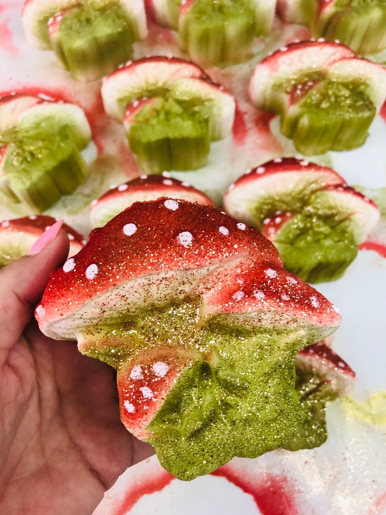 May include: A collection of red and green glitter mushroom shaped ornaments. The mushrooms have white polka dots and are made of a soft, spongy material.
